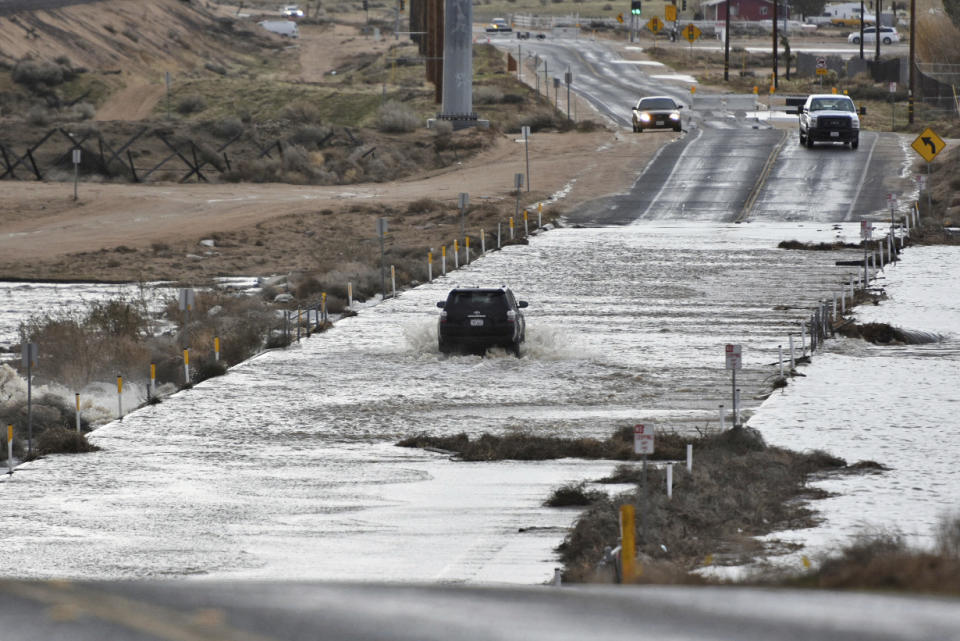 A vehicle crosses a closed off flooded section of Rock Springs Road in Hesperia, Calif., on Monday, Jan., 23, 2017. The tail end of a punishing winter storm system lashed California with thunderstorms and severe winds Monday after breaking rainfall records, washing out roads and whipping up enormous waves. (David Pardo/The Daily Press via AP)