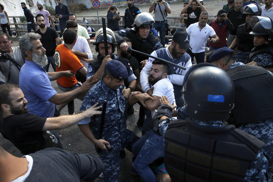 Hezbollah supporters clash with Lebanese riot policemen during a protest in Beirut, Lebanon, Tuesday, Oct. 29, 2019. Beirut residents have scuffled with Lebanese protesters blocking a main thoroughfare, prompting riot police to move to separate them. The tension Tuesday comes on the 13th day of anti-government protests. (AP Photo/Bilal Hussein)