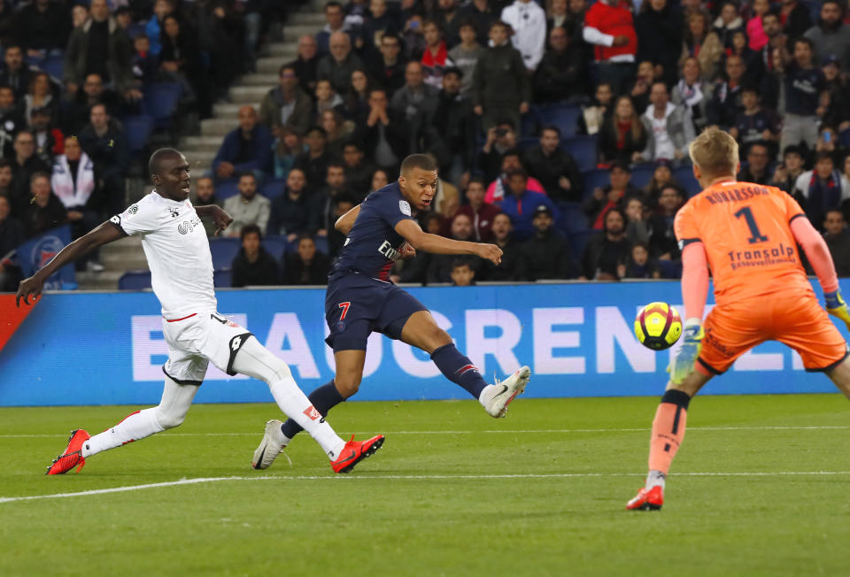 PSG's Kylian Mbappe kicks the ball ahead of Dijon goalkeeper Runar Alex Runarsson, right, and Dijon's Cedric Yambere during their League One soccer match between Paris Saint Germain and Dijon at the Parc des Princes stadium in Paris, France, Saturday, May 18, 2019. (AP Photo/Francois Mori)