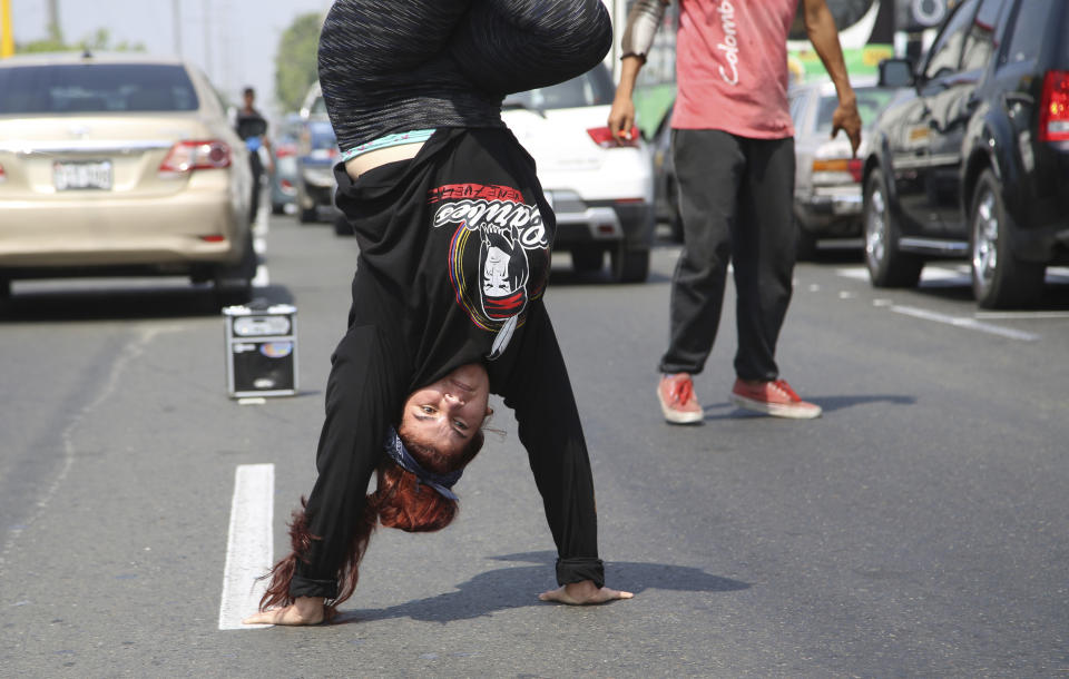 In this Dec. 12, 2018 photo, Venezuelan Liliana Molina breakdances in the street for tips from commuters in Lima, Peru. Venezuelans are fighting for survival after fleeing the worst economic crisis anybody in Latin America can remember. (AP Photo/Cesar Olmos)