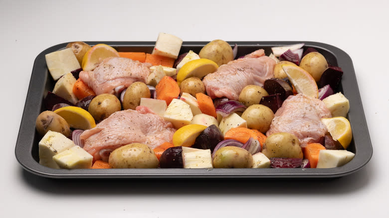 uncooked chicken and vegetables on sheet pan