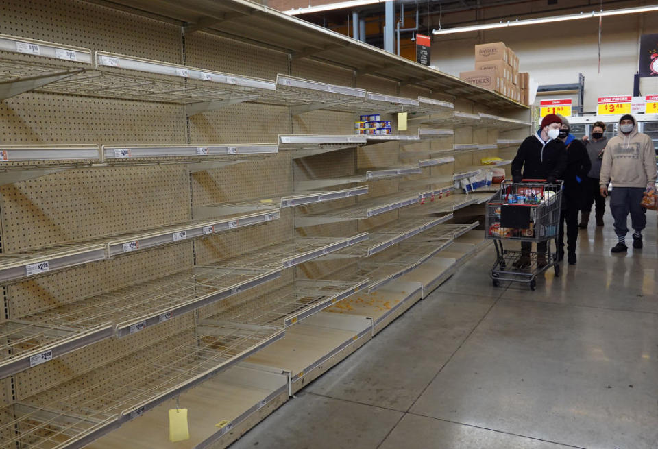 Shoppers walk past a bare shelf as people stock up on necessities in Texas amid supply fears. Source: Getty