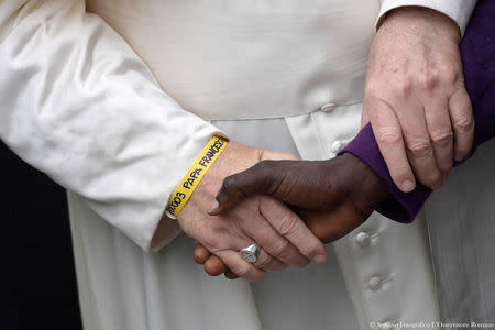 Pope Francis wears a yellow plastic ID bracelet as he shakes hand with a man during a visits at a migrant's reception centre during a pastoral visit in Bologna, Italy October 1, 2017. Osservatore Romano/Handout via Reuters