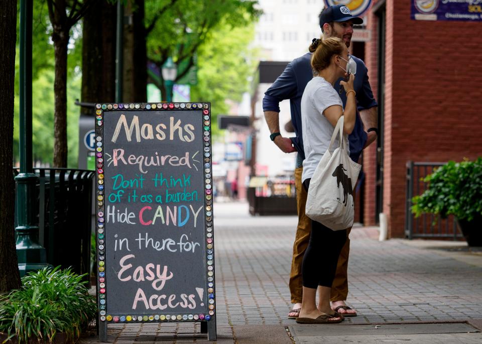 Ryan Furey stands with Monique Howard as she puts on her mask as she contemplates entering Rocket Fizz in Chattanooga, Tenn.