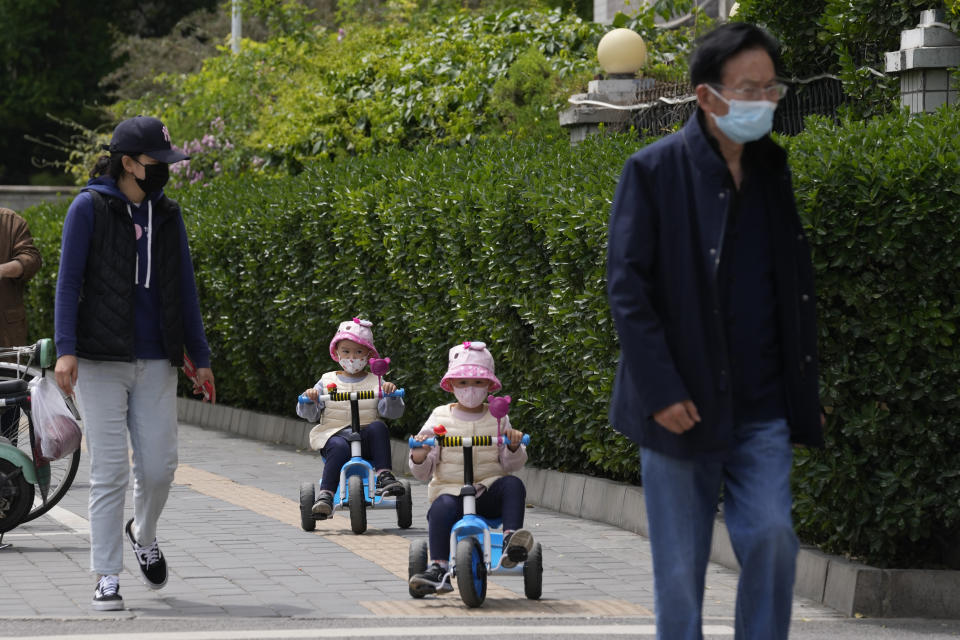 Young residents wearing masks cycle down a path on Monday, May 9, 2022, in Beijing. (AP Photo/Ng Han Guan)