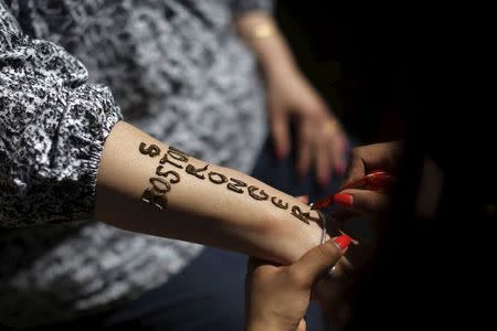 A woman gets the words "Boston Stronger" written on her arm near the finish line on the second anniversary of the Boston Marathon bombings in Boston, Massachusetts April 15, 2015. REUTERS/Brian Snyder