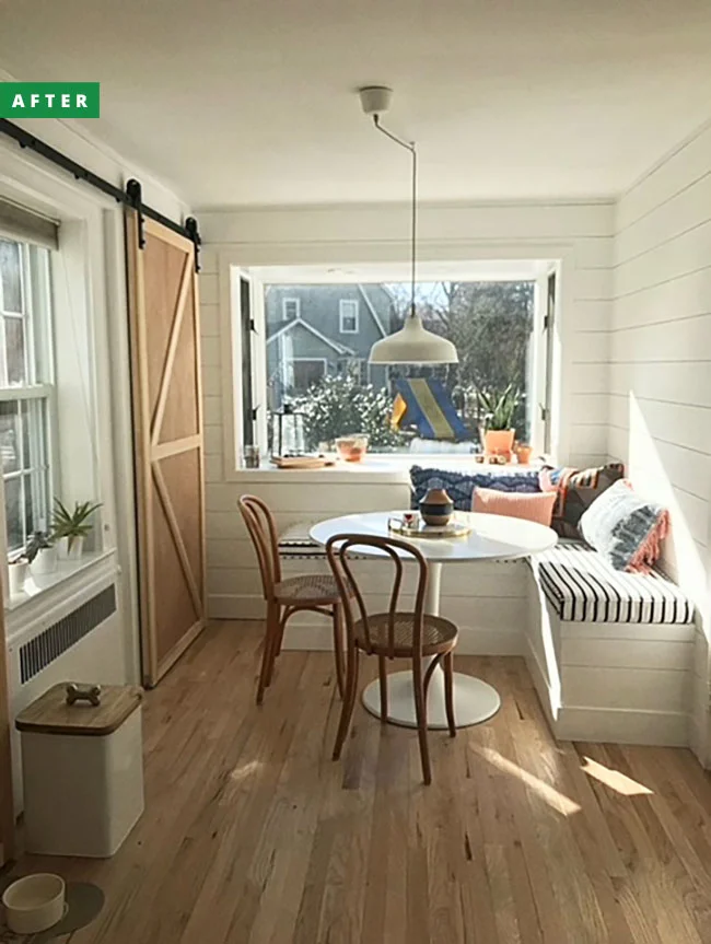 A breakfast nook after renovation with a banquette and barn door.