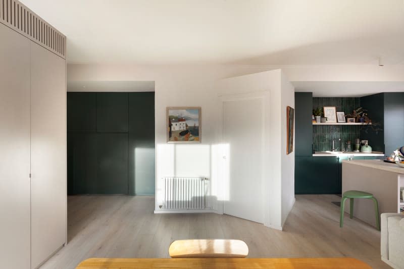 Hallway with green built-in murphy bed, white walls with framed artwork.