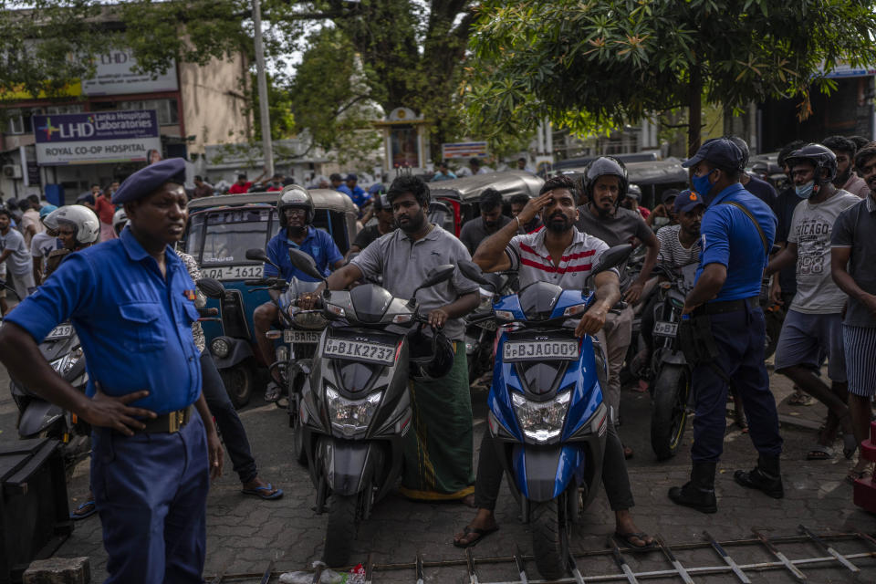 Police officers stand guard as people wait in queue to buy petrol at a fuel station, in Colombo, Sri Lanka, July 17, 2022. Bankruptcy has forced the island nation's government to a near standstill. Parliament is expected to elect a new leader Wednesday, paving the way for a fresh government, but it is unclear if that's enough to fix a shattered economy and placate a furious nation of 22 million that has grown disillusioned with politicians of all stripes. (AP Photo/Rafiq Maqbool)