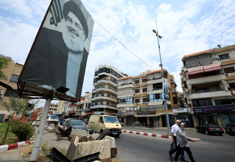 People walk past a poster depicting Lebanon's Hezbollah leader Sayyed Hassan Nasrallah, near Sidon