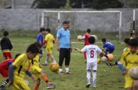 In this picture taken on Monday, April 28, 2014, Iranian man Abdolghani Hosseinzadeh, center, whose son was killed in a street brawl, coaches children and teens at the Derakhshan Soccer School in the city of Royan about 146 miles (235 kilometers) north of the capital Tehran, Iran. His wife Samereh Alinejad tells The Associated Press that she had felt she could never live with herself if the man who killed her son Abdollah were spared from execution. But in the last moment, she pardoned him in an act that has made her a hero in her hometown, where banners in the streets praise her family’s mercy. (AP Photo/Vahid Salemi)