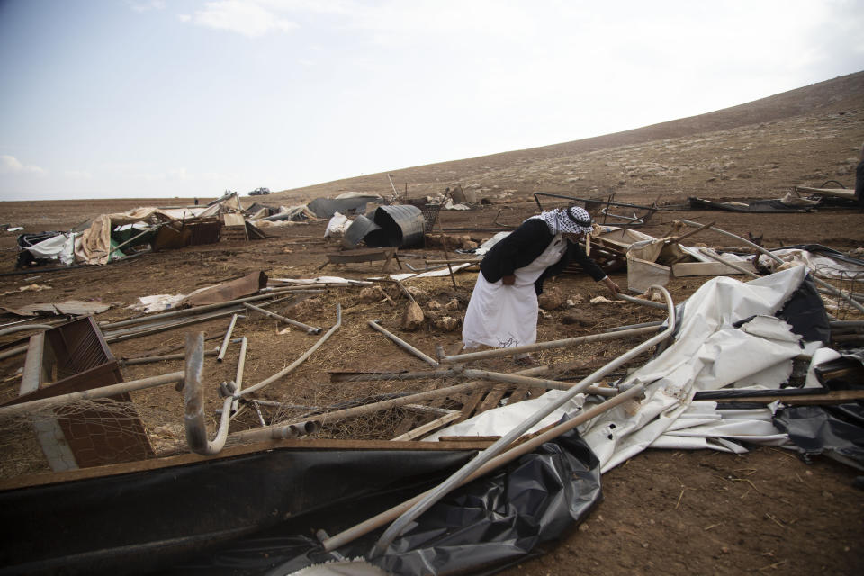 A Palestinian sifts through destroyed tents in Khirbet Humsu in Jordan Valley in the West Bank, Friday, Nov. 6, 2020. Israeli troops with bulldozers and heavy equipment demolished 18 tents and other structures that housed 74 people, including 41 minors, according to the Israeli rights group B'Tselem. COGAT, the Israeli military body in charge of civilian affairs in the West Bank, said an "enforcement activity" was carried out against seven tents and eight pens that were "illegally constructed" in a firing range. (AP Photo/Majdi Mohammed)