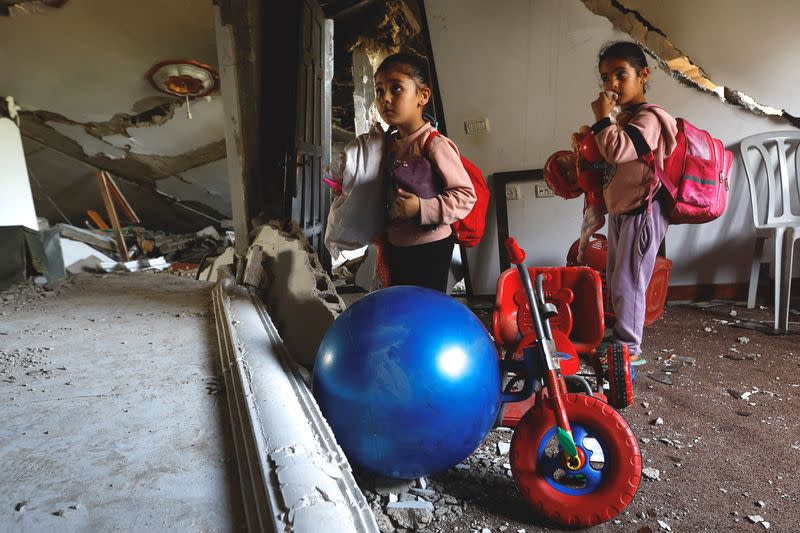 Palestinian girls collect their stuff from their house which was destroyed in Israeli air strikes, in Deir al-Balah town