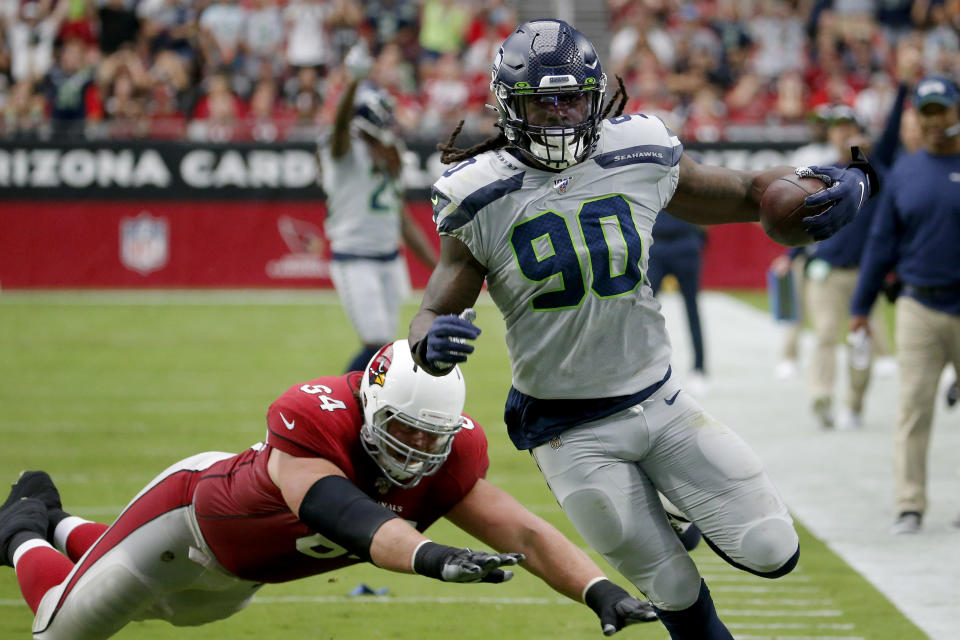 Seattle Seahawks outside linebacker Jadeveon Clowney (90) runs back an interception for a touchdown as Arizona Cardinals offensive guard J.R. Sweezy (64) defends during the first half of an NFL football game, Sunday, Sept. 29, 2019, in Glendale, Ariz. (AP Photo/Rick Scuteri)