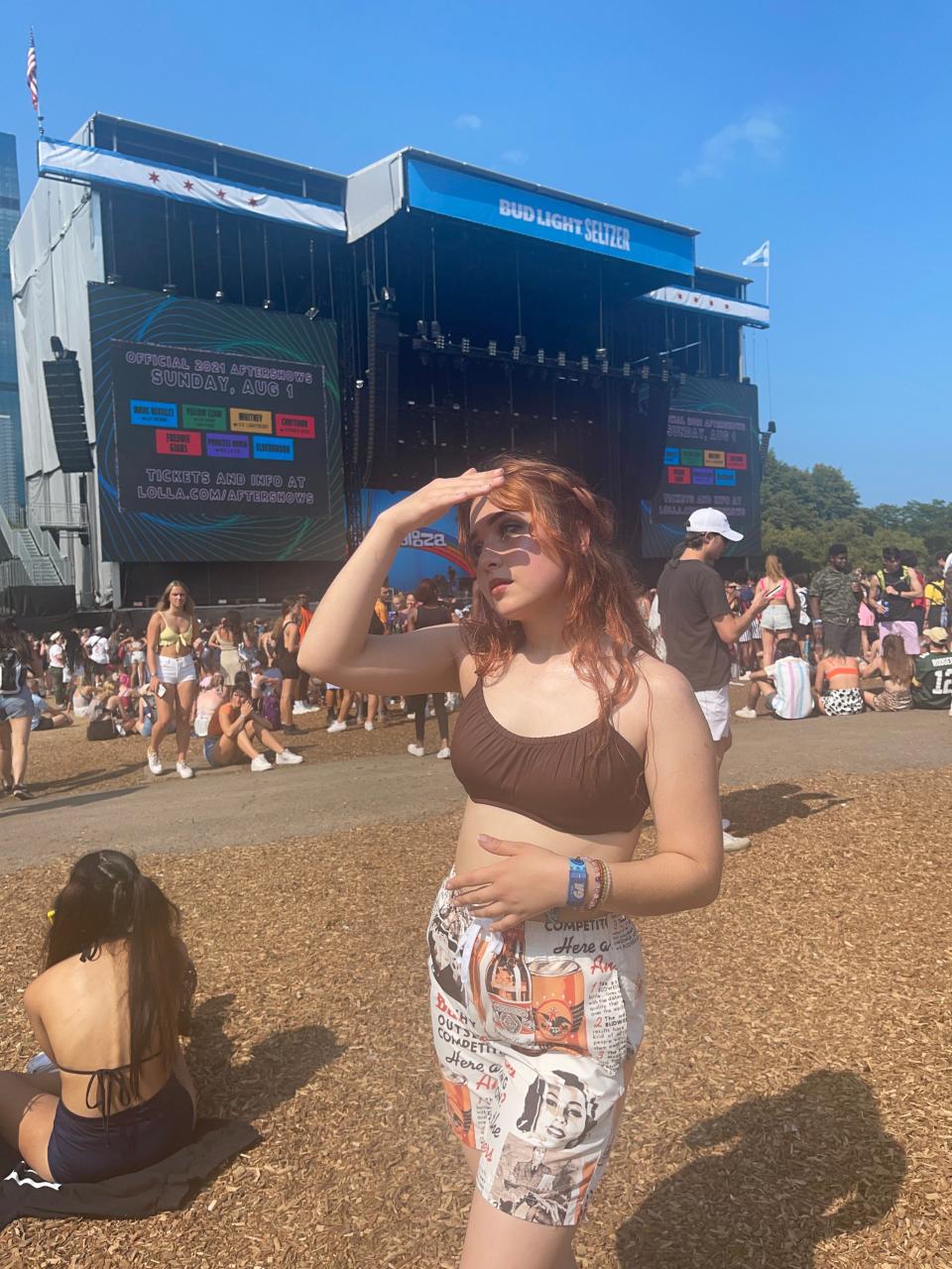 A person shades her face in front of an outdoor music stage