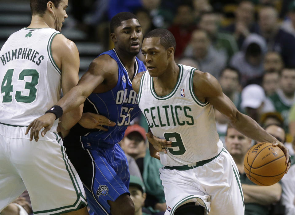 Rajon Rondo, de los Celtics de Boston, busca un compañero para enviarle el balón, mientras dribla a E'Twaun Moore, del Magic de Orlando, en el partido del domingo 2 de febrero de 2014 (AP Foto/Steven Senne)