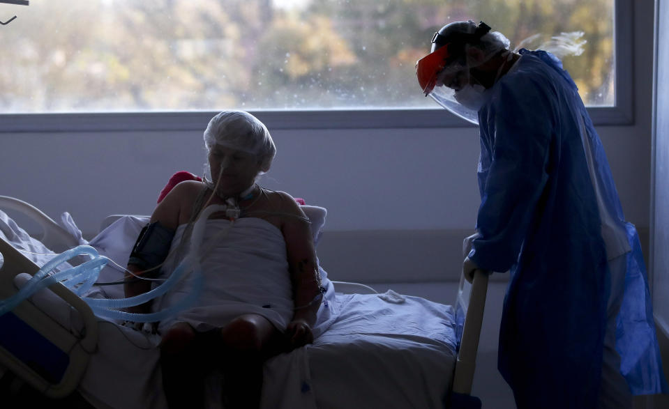 Un trabajador de la salud atiende a un paciente en una unidad de cuidados intensivos designada para personas infectadas con COVID-19 en un hospital en Buenos Aires, Argentina, el viernes 2 de octubre de 2020. (AP Foto/Natacha Pisarenko)