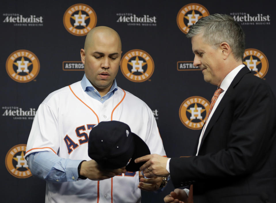 FILE - In this Dec. 5, 2016, file photo, Houston Astros general manager Jeff Luhnow, right, hands outfielder Carlos Beltran a cap during a news conference to announce Beltran's signing a one-year contract with the team, in Houston. Beltran is out as manager of the New York Mets. The team announced the move Thursday, Jan. 16, 2020. (AP Photo/David J. Phillip, File)