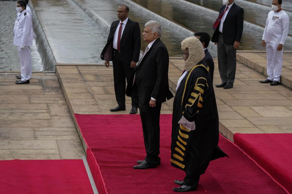 Sri Lankan president Ranil Wickremesinghe, center, inspects a military guard of honour standing next to the speaker of the parliament Mahinda Yapa Abeywardena after arriving at the parliamentary complex in Colombo, Sri Lanka, Wednesday, Aug. 3, 2022. (AP Photo/Eranga Jayawardena)