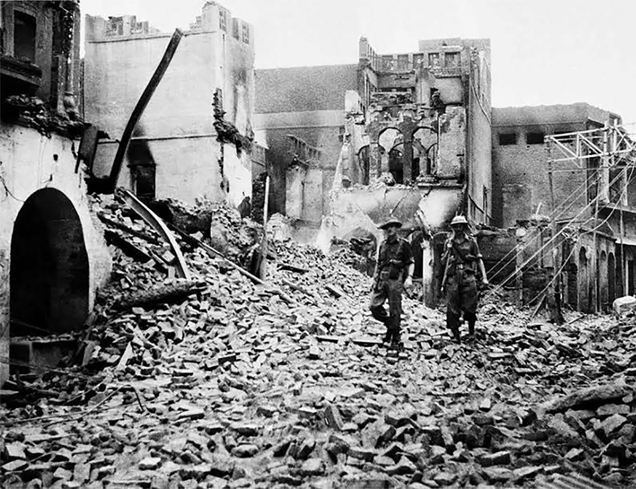 Indian soldiers walk through the debris of a building in the Chowk Bijli Wala area of Amristar during unrest following the Partition of India and Pakistan, August 1947. (AFP via Getty Images)