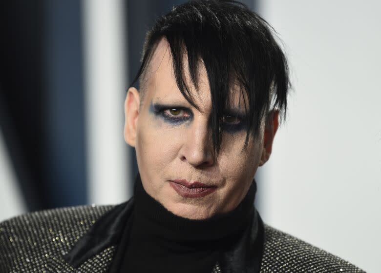 A man with dark hair wearing eye makeup and lipstick