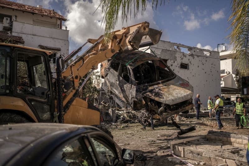 An excavator removes a destroyed vehicle in Kiryat Bialik, following a reported strike by the pro-Iranian Hezbollah movement. Ilia Yefimovich/dpa