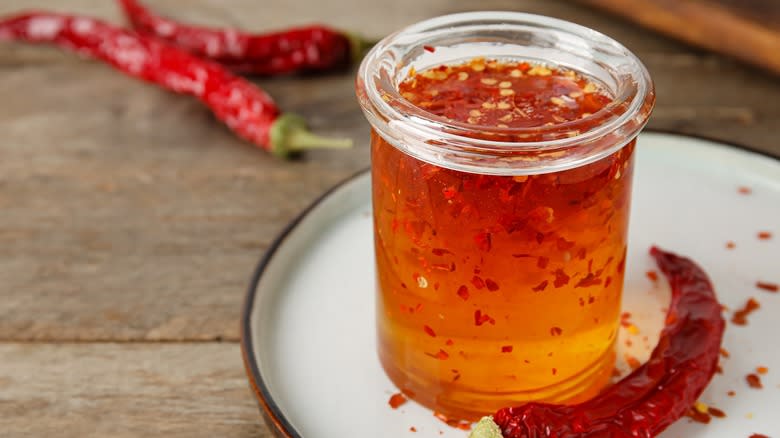 A glass jar of hot honey with red chili flakes and chiles