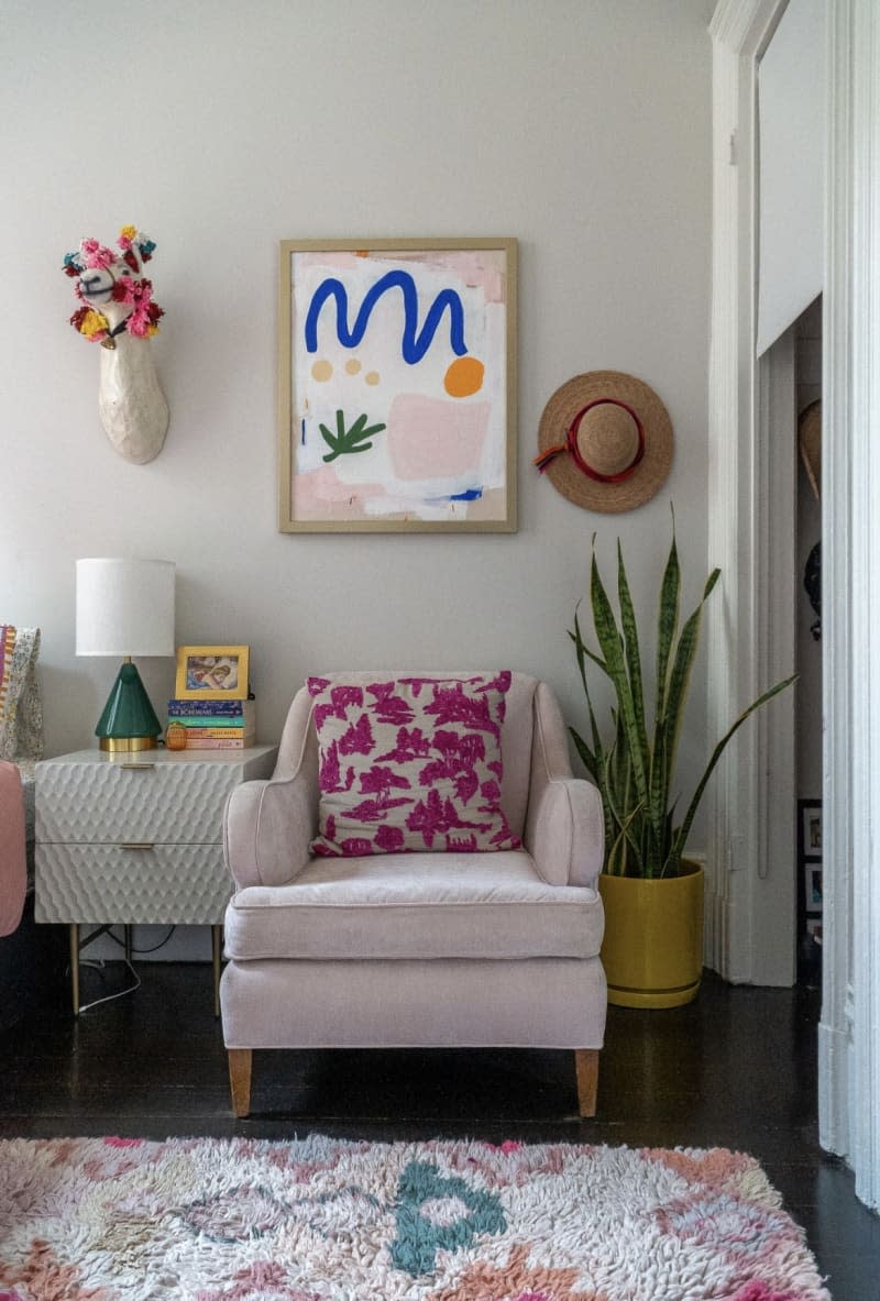 Corner of white living room with pink armchair and colorful details