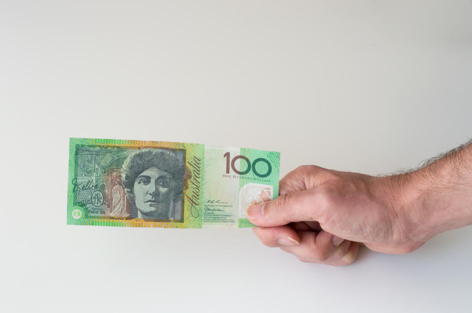 Man holding  hundred Australian Dollar banknote in his hands