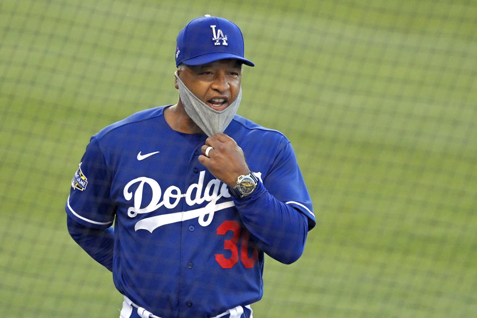 Los Angeles Dodgers manager Dave Roberts pulls down his mask to talk to someone in the dugout from a distance during an intrasquad baseball game Wednesday, July 8, 2020, in Los Angeles. (AP Photo/Mark J. Terrill)