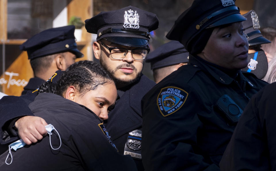 Police officers embrace after the remains of New York City Police Department Officer Wilbert Mora arrived at a funeral home in the Manhattan borough of New York, Wednesday, Jan. 26, 2022. Officer Mora, who died Tuesday, was gravely wounded last week in a Harlem shooting that also killed his partner. (AP Photo/Craig Ruttle)