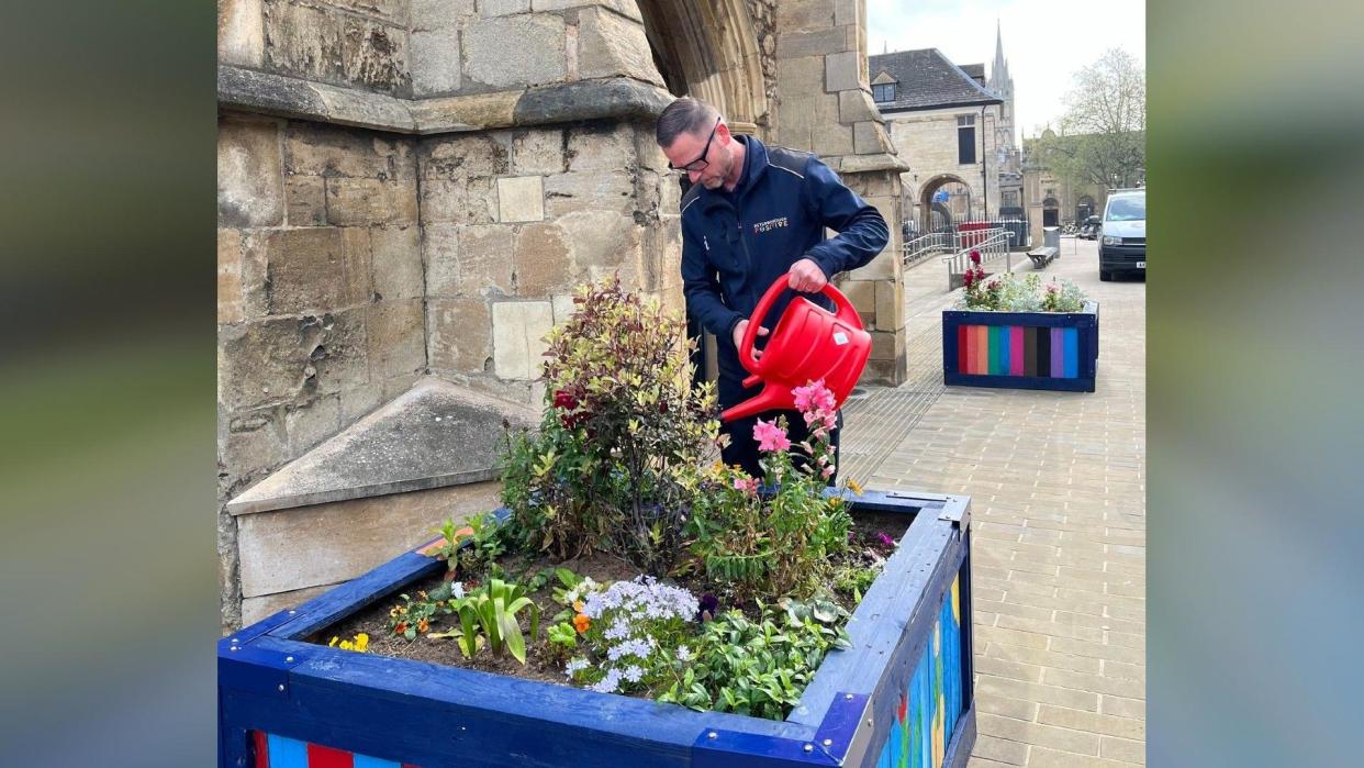 Terry watering a wooden planter - with a red watering can 