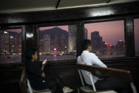 In this Oct. 10, 2019 photo, people ride in a ferry from Hong Kong Island to Kowloon as the sun sets in Hong Kong. The body-blow of months of political protests on Hong Kong’s tourism is verging on catastrophic for one of the world’s great destinations. Geared up to receive 65 million travelers a year, the city’s hotels, retailers, restaurants and other travel-oriented industries are suffering. But some intrepid visitors came specifically to see the protests and are reveling in deep discounts and unusually short lines at tourist hotspots. (AP Photo/Felipe Dana)