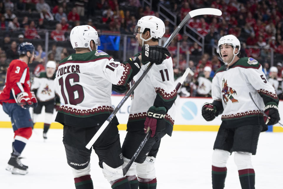 Arizona Coyotes right wing Dylan Guenther (11) is congratulated by left wing Jason Zucker (16) and defenseman Michael Kesselring (5) after scoring a goal during the second period of an NHL hockey game against the Washington Capitals, Sunday, March 3, 2024, in Washington. (AP Photo/Manuel Balce Ceneta)