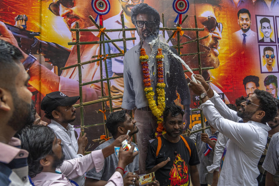 Indian fans sprinkle milk on a cutout of their superstar Rajinikanth, outside a cinema hall as they celebrate the screening of his latest film "Jailer" in Mumbai, India, Thursday, Aug. 10, 2023. (AP Photo/Rafiq Maqbool)
