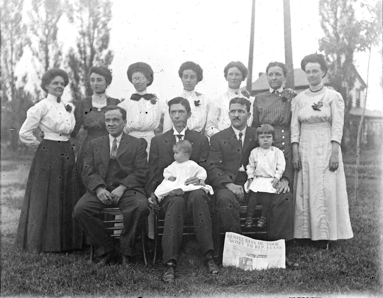 A Cleveland Press newspaper from June 1911 is used to document the date of a family portrait. The headline reads “KEMPEL SAYS HE TOOK MONEY TO. REP. EVANS.” We still don’t know the names of the people pictured. Recognize anyone?