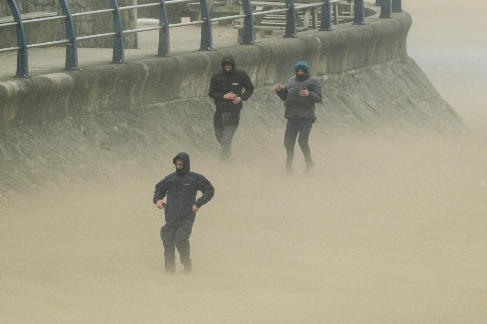 People walk in high winds along the seafront in Newquay on the Cornish coast as Storm Eunice makes landfall. Picture date: Friday February 18, 2022.