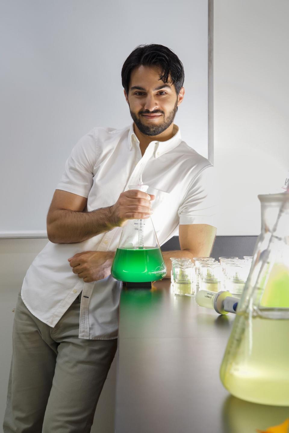 René Shahmohamadloo is an ecotoxicologist and postdoctoral scientist shown holding holding a flask of cyanobacteria.