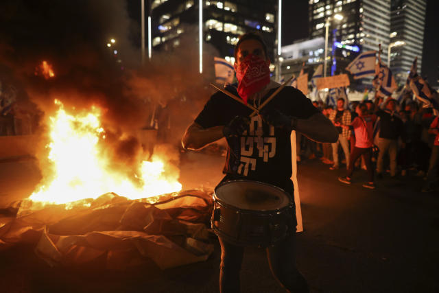 Israelis opposed to Prime Minister Benjamin Netanyahu's judicial overhaul plan set up bonfires and block a highway during a protest moments after the Israeli leader fired his defense minister, in Tel Aviv, Israel, Sunday, March 26, 2023. Defense Minister Yoav Gallant had called on Netanyahu to freeze the plan, citing deep divisions in the country and turmoil in the military. (AP Photo/Oren Ziv)