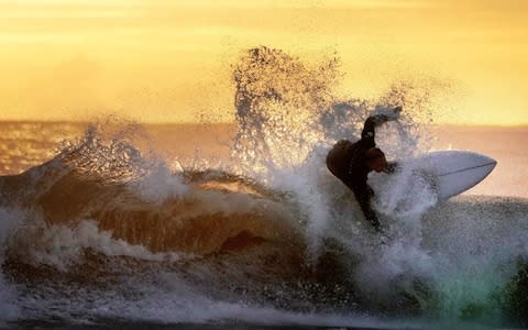 A surfer in action during sunrise at Tynemouth on the north east coat - Credit: Owen Humphreys/PA