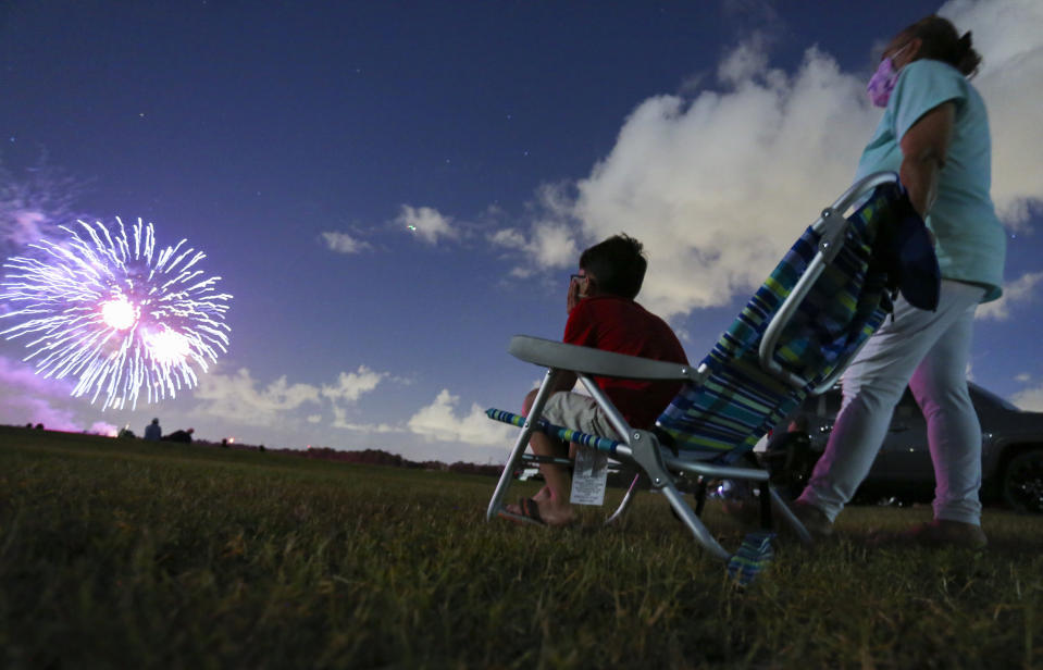 Javonnie Jackson, 9, left, sits with his grandmother Zoraida Rullan, 69, watching fireworks explode over Nathan Benderson Park on Friday, July 3, 2020, in Sarasota, Fl. The pair were reunited after nearly five months of separation due to the coronavirus. (Jonah Hinebaugh/Tampa Bay Times via AP)