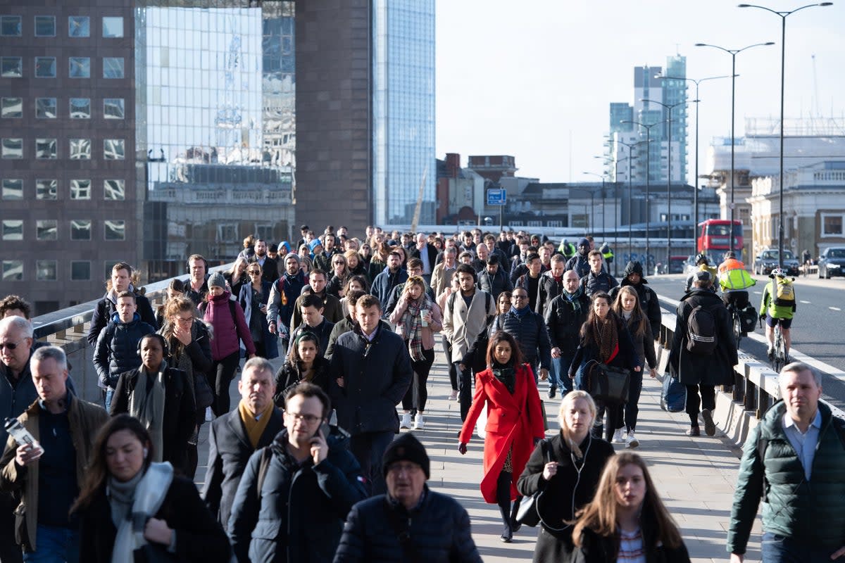 Commuters cross London Bridge  (PA)