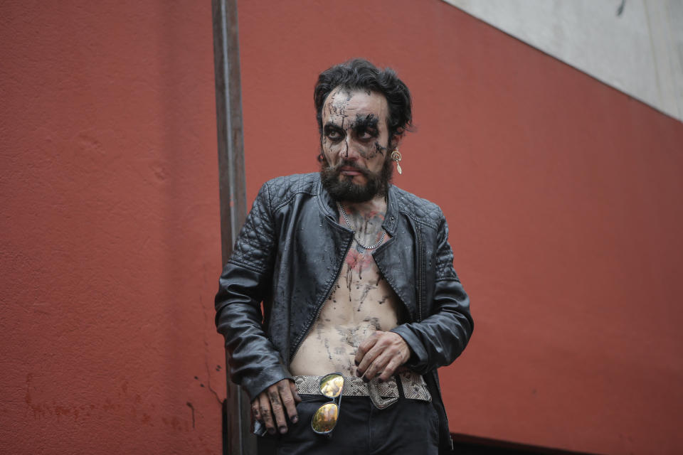 A man who was sprayed with black ink by demonstrators watches as they they continue their protest in Mexico City, Saturday Sept. 28, 2019. Mexican women on Saturday marched for abortion rights, highlighting increased efforts across Latin America to lift some of the world's most restrictive abortion laws. (AP Photo/Anthony Vazquez)