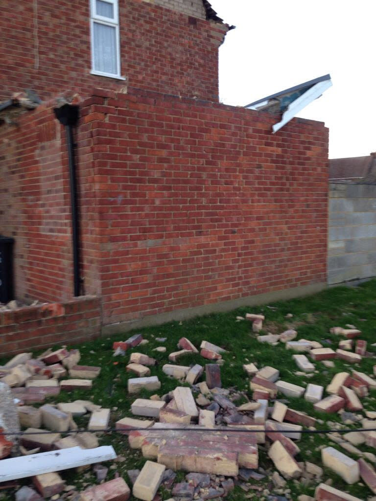 Bricks are seen scattered across the lawn after a huge section of the wall fell (SWNS)