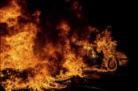 A car catches fire next to a burning barricade during clashes between protestors and police in Barcelona, Spain, Wednesday, Oct. 16, 2019. Spain's government said Wednesday it would do whatever it takes to stamp out violence in Catalonia, where clashes between regional independence supporters and police have injured more than 200 people in two days. (AP Photo/Bernat Armangue)