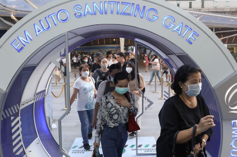 People walk through a 'sanitising gate' spraying disinfectants against coronavirus before entering into a shopping mall in Bangkok