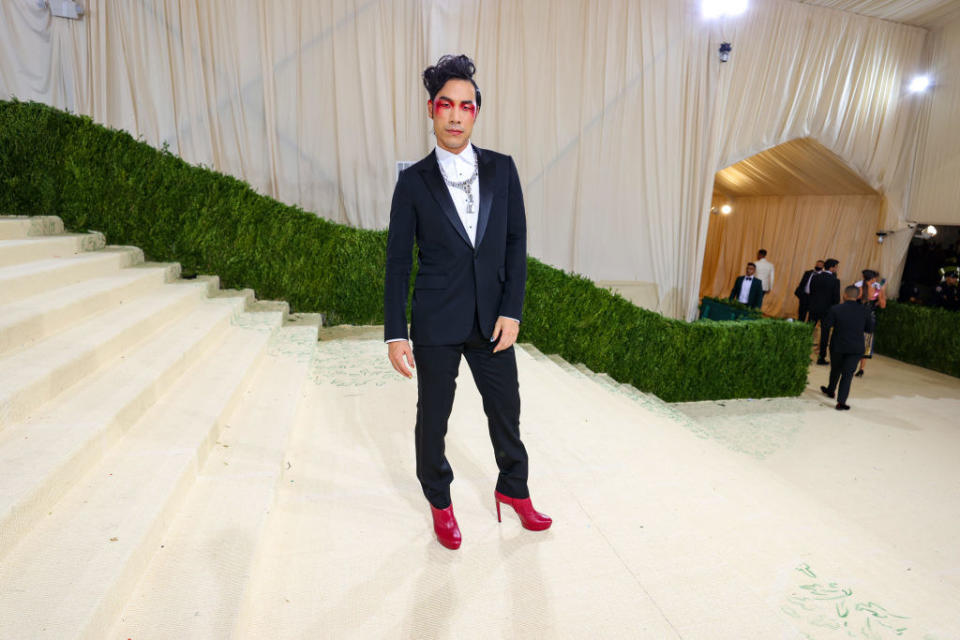 Eugene Lee Yang wears a dark suit and brightly colored heels