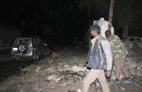 Police officers assess the scene of an explosion outside the Jazira hotel in Mogadishu, January 1, 2014. Three bombs exploded within an hour outside the hotel in a heavily fortified district of the Somali capital on Wednesday, killing at least 11 people. (REUTERS/Feisal Omar)