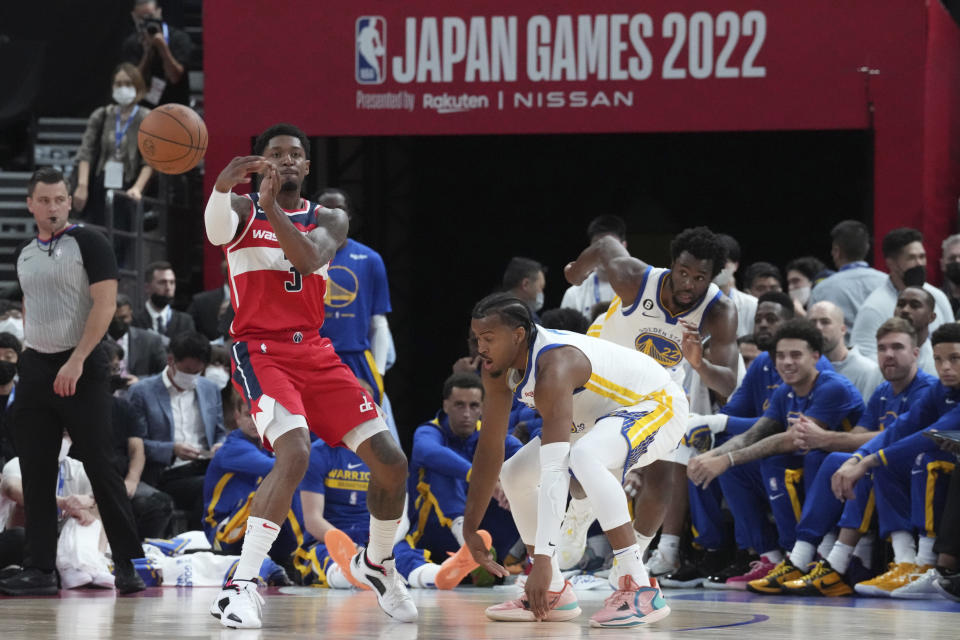 Washington Wizards' Bradley Beal, left, passes the ball around Golden State Warriors' Moses Moody, front right, and Andrew Wiggins during the preseason NBA basketball game, Friday, Sept. 30, 2022, at Saitama Super Arena, in Saitama, north of Tokyo. (AP Photo/Eugene Hoshiko)