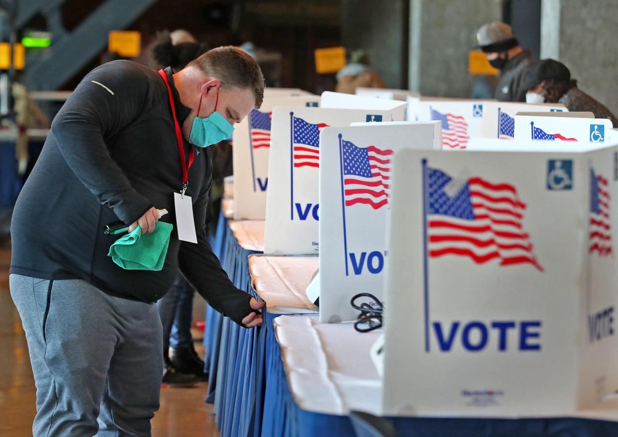 Clerk Sam Snideman cleans voting stations between voters during early voting at Lucas Oil Stadium on Saturday, Oct. 31, 2020. The county election board added the site to help relieve long lines at other early voting sites. The stadium held 56 voting machines.